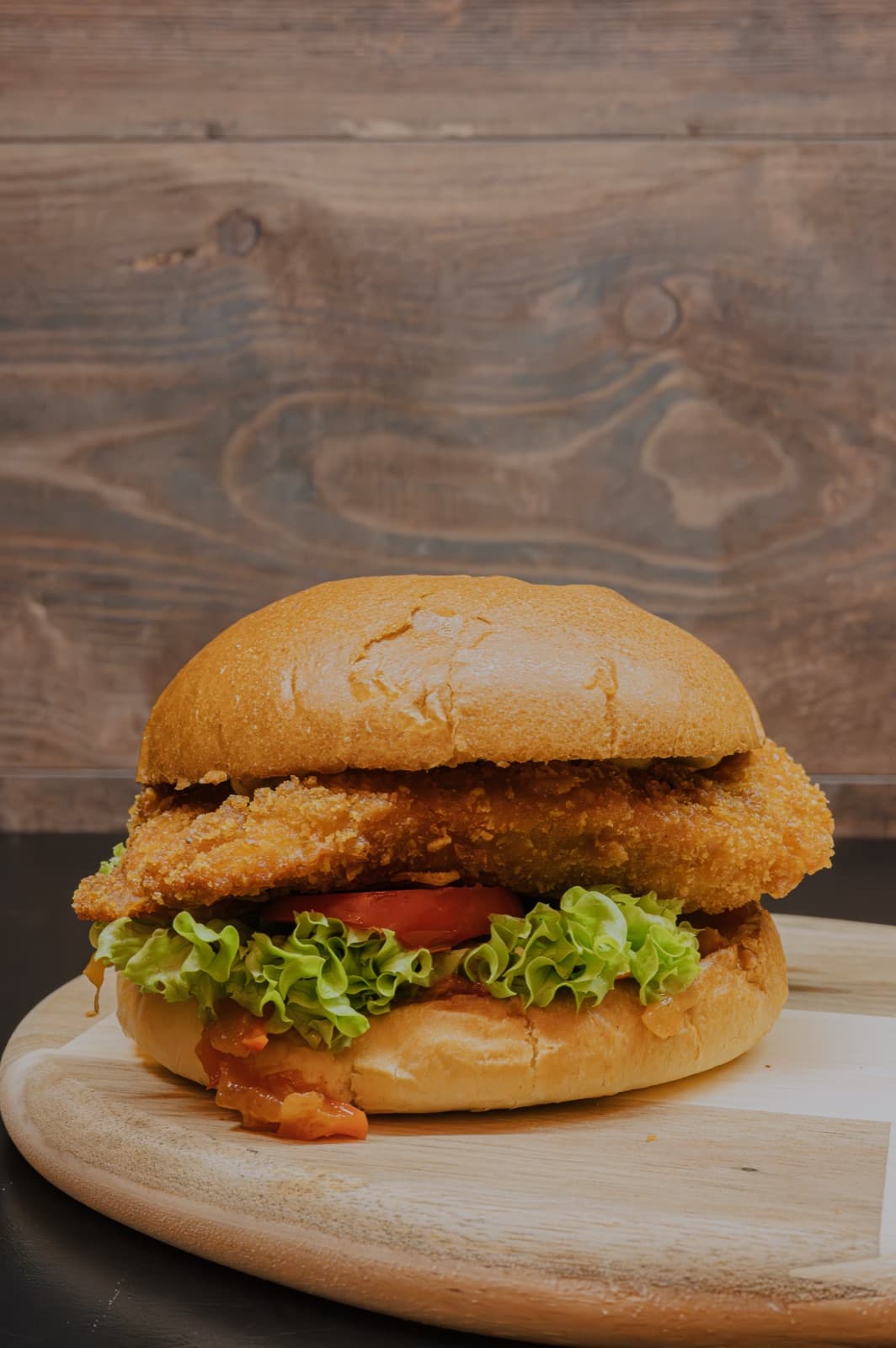 Krokante burger op een houten plank bij Frituur Frinesse