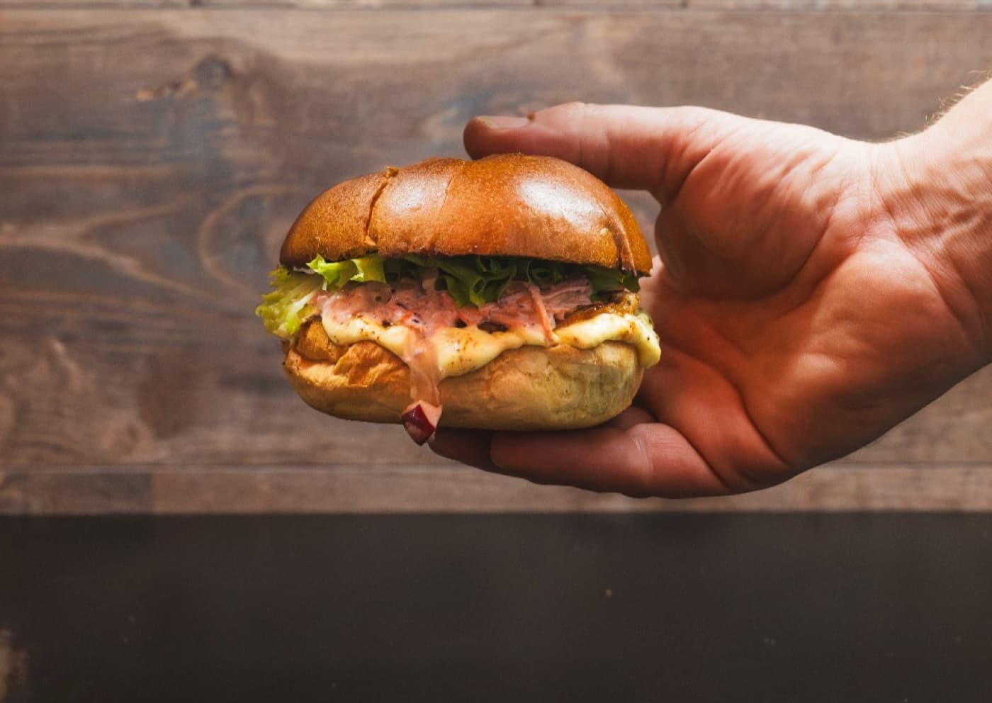 Burger van Frituur Frinesse tegen een warme houten achtergrond